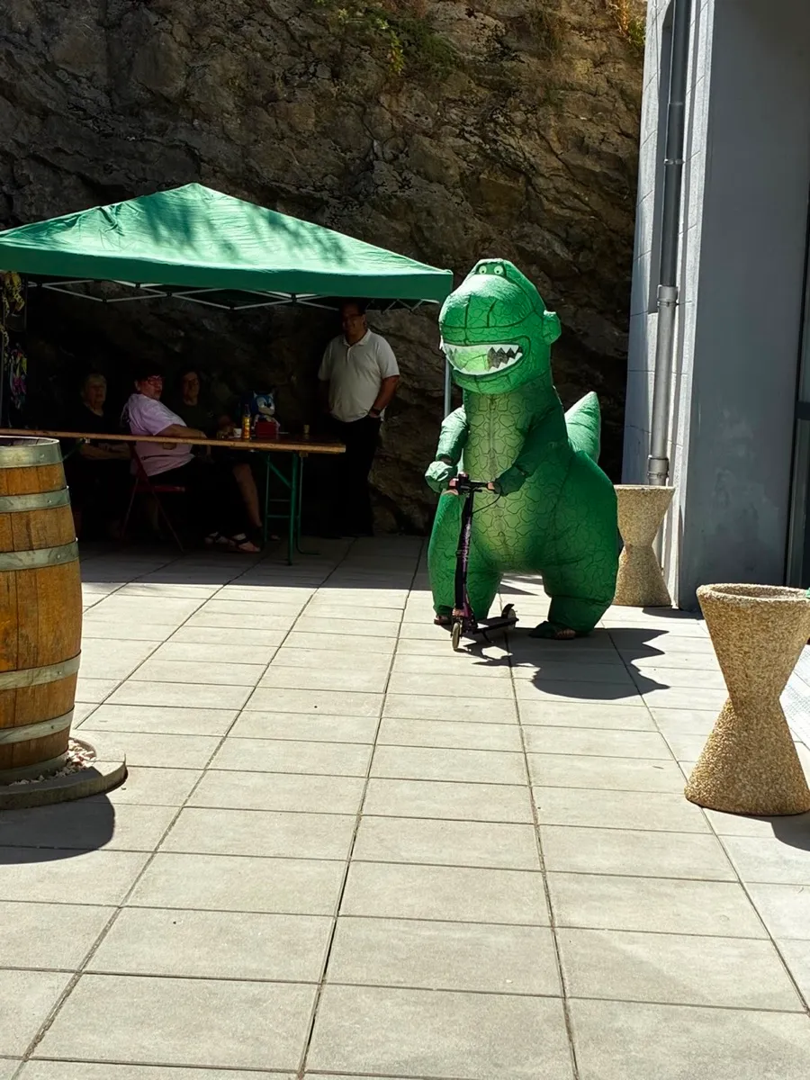 La mascotte T-Rex en trottinette dans les allées